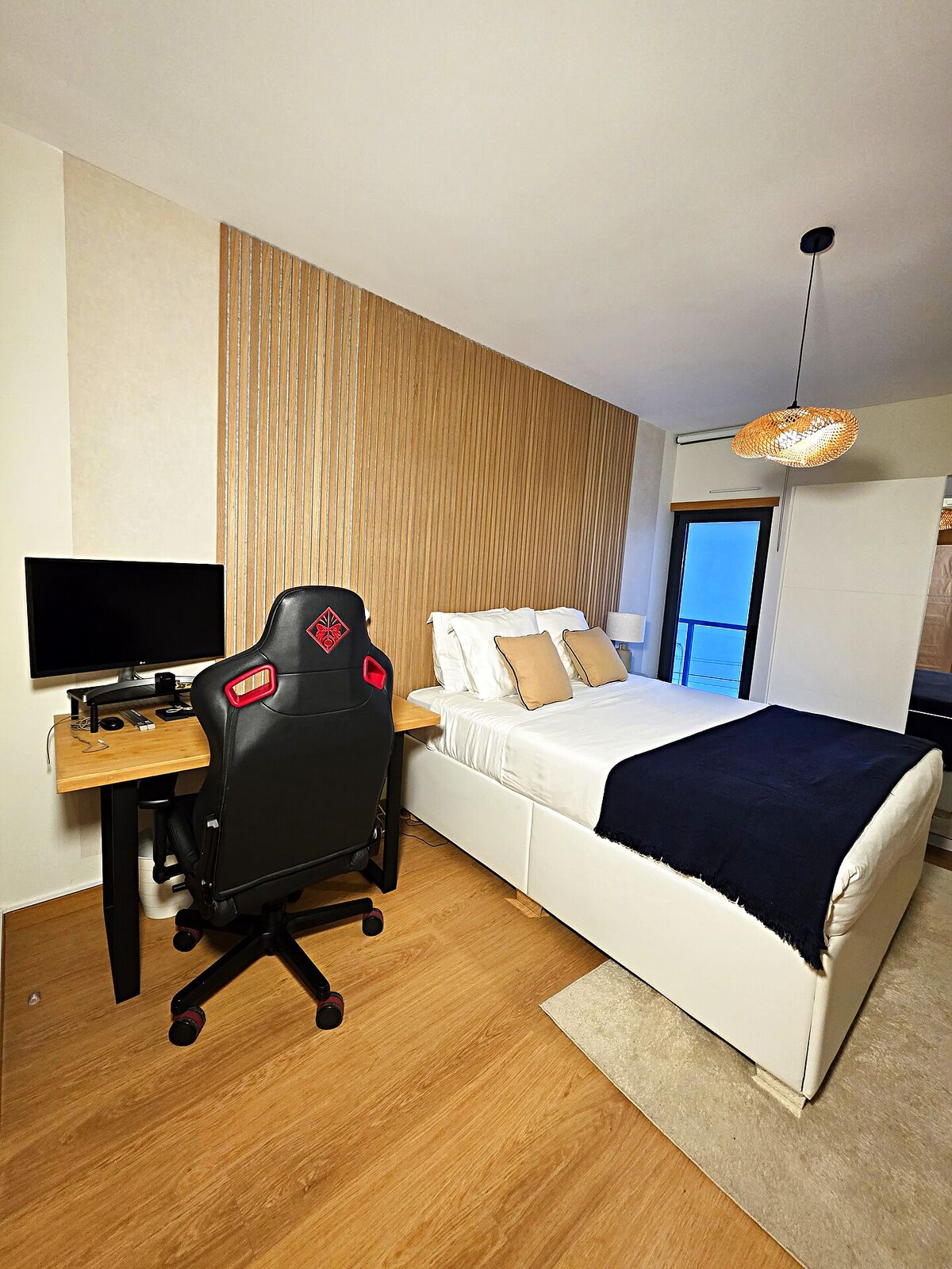 A Survana bedroom set up as a workspace with a desk, monitor and ergonomic chair by the window