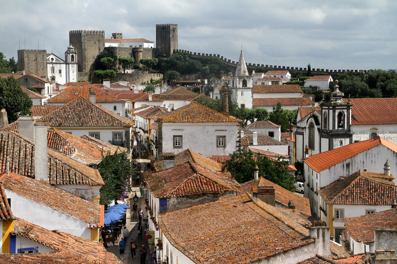 Terracotta rooftops of the walled town of Óbidos with the castle on the hill behind