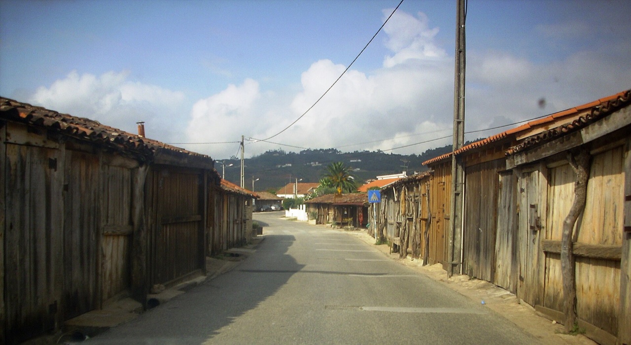 Sunlit lane running between rows of wooden salt-workers' huts at Rio Maior