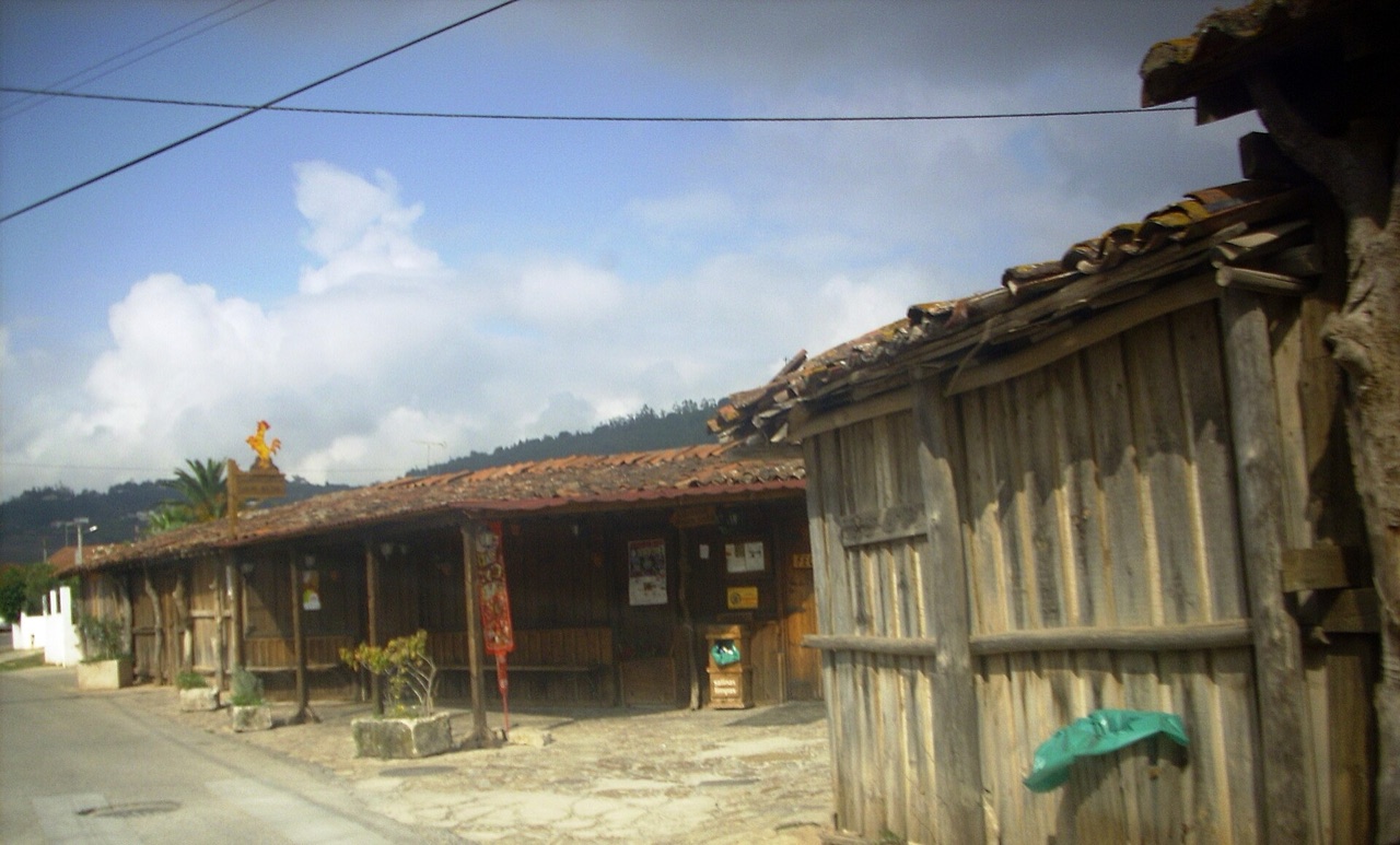 Row of wooden palheiro salt huts under a blue sky at Salinas de Rio Maior
