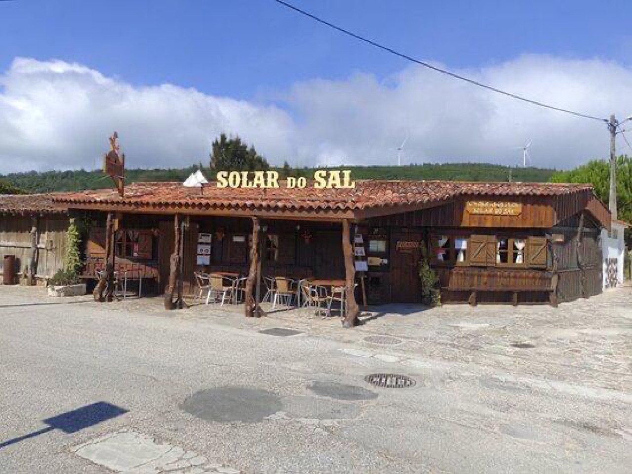 Solar do Sal restaurant exterior with carved wooden signage and windmills on the hill behind