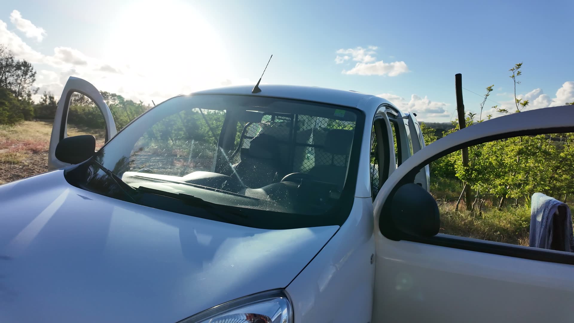 Front three-quarter of the Kangoo with every door open and golden-hour sun flare