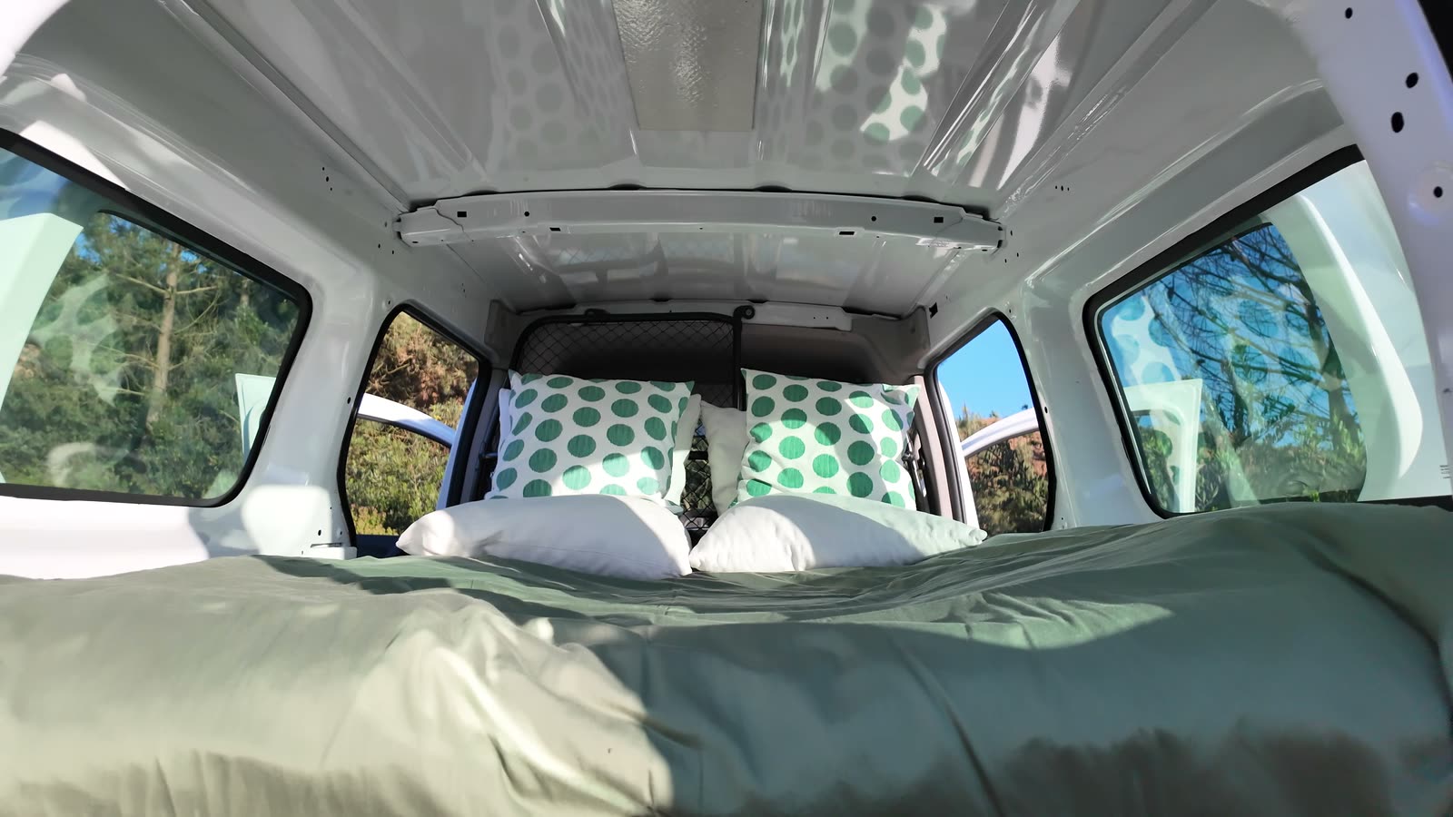Wide view of the roomy interior with the full bed made up and pillows